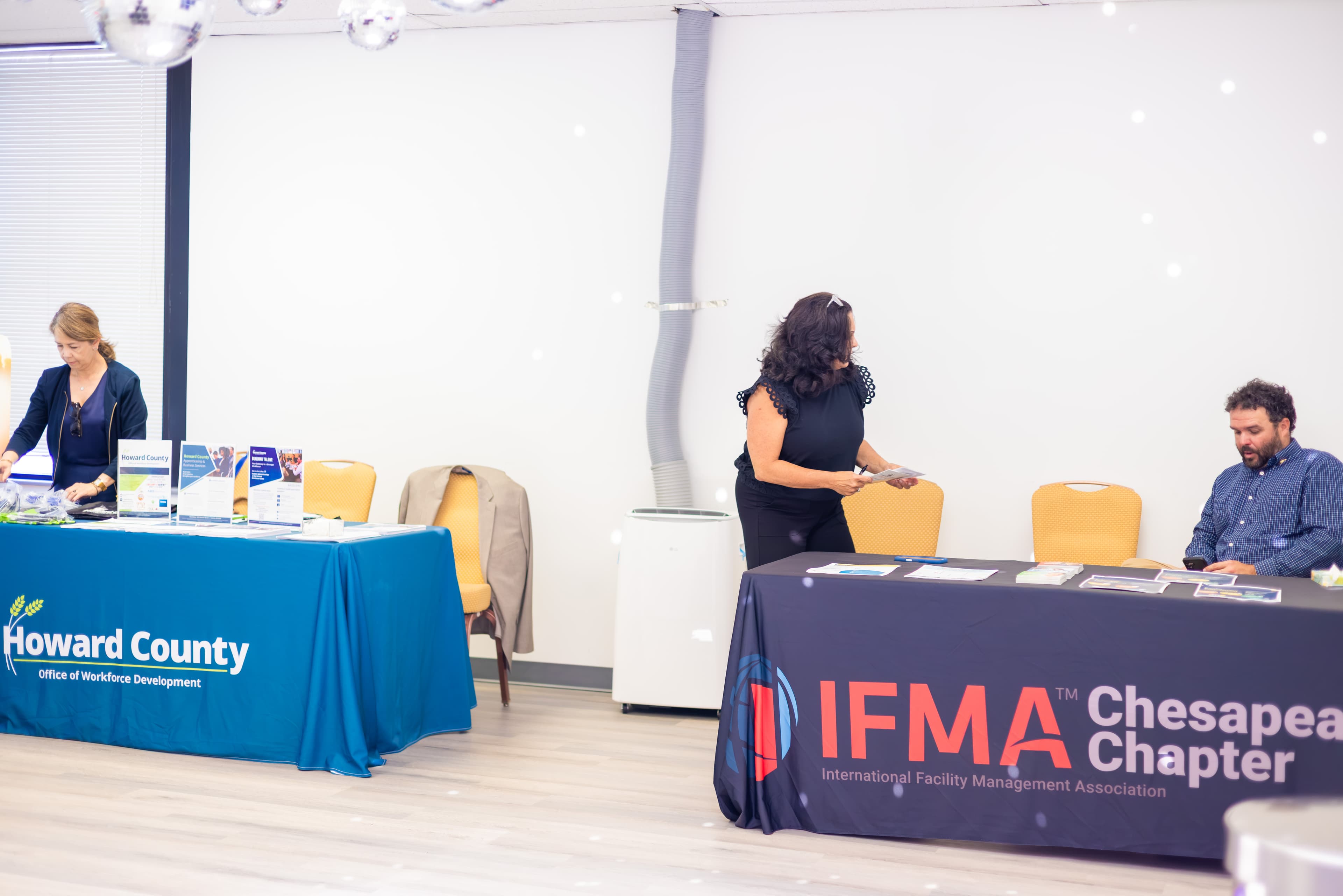 Staff members organize informational tables for Howard County and IFMA at a professional event.