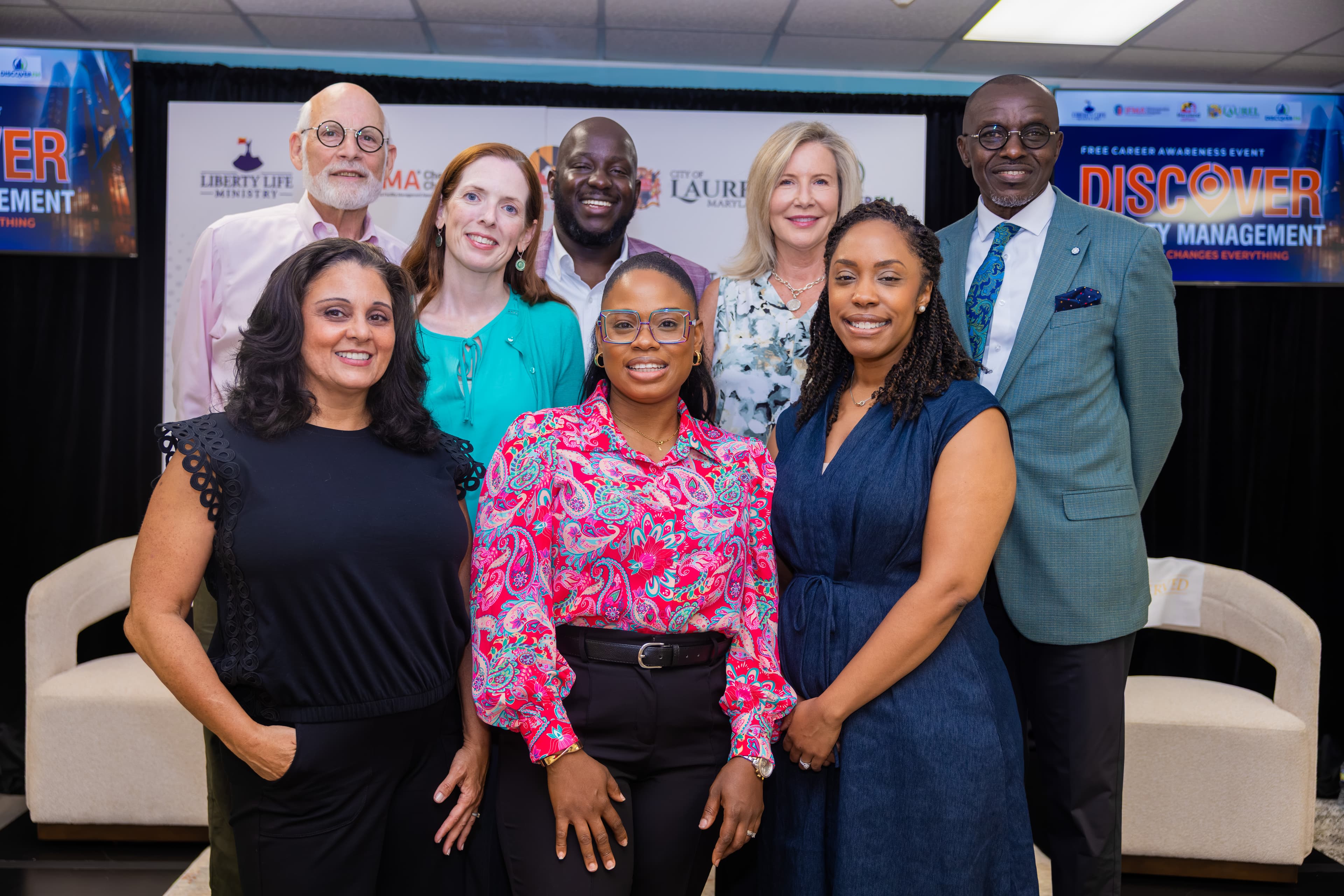 Eight diverse professionals smiling together at a career awareness event for property management.